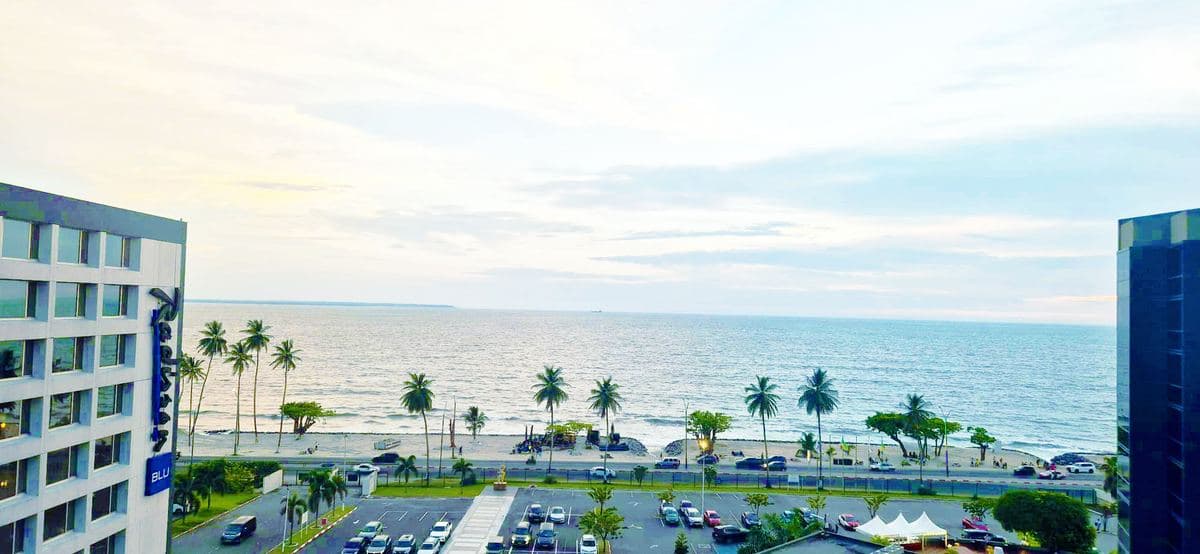 Vue du bord de mer de Libreville depuis un immeuble, avec ses palmiers et sa plage.